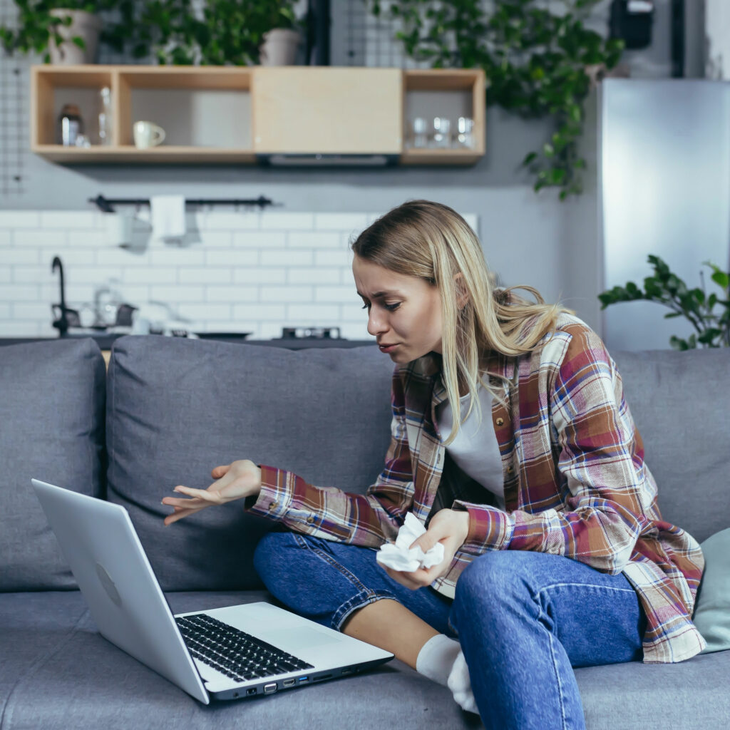 junge Frau sitzt Zuhause mit ihrem Laptop bei einer Online-Therapiestunde