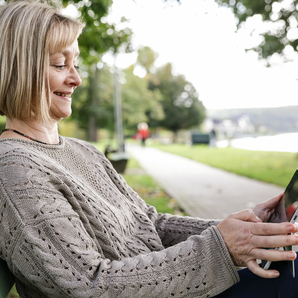 Natja du preez sitzt in einem Park mit ihrem Tablet